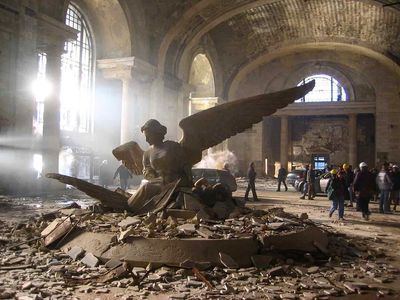 a statue of an angel sitting on top of a pile of rubble