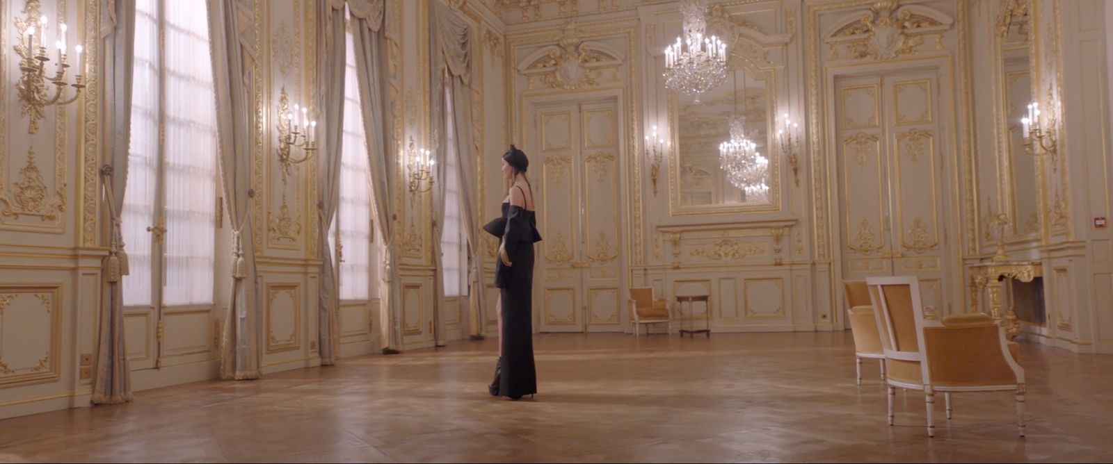 a woman standing in a room with chandeliers