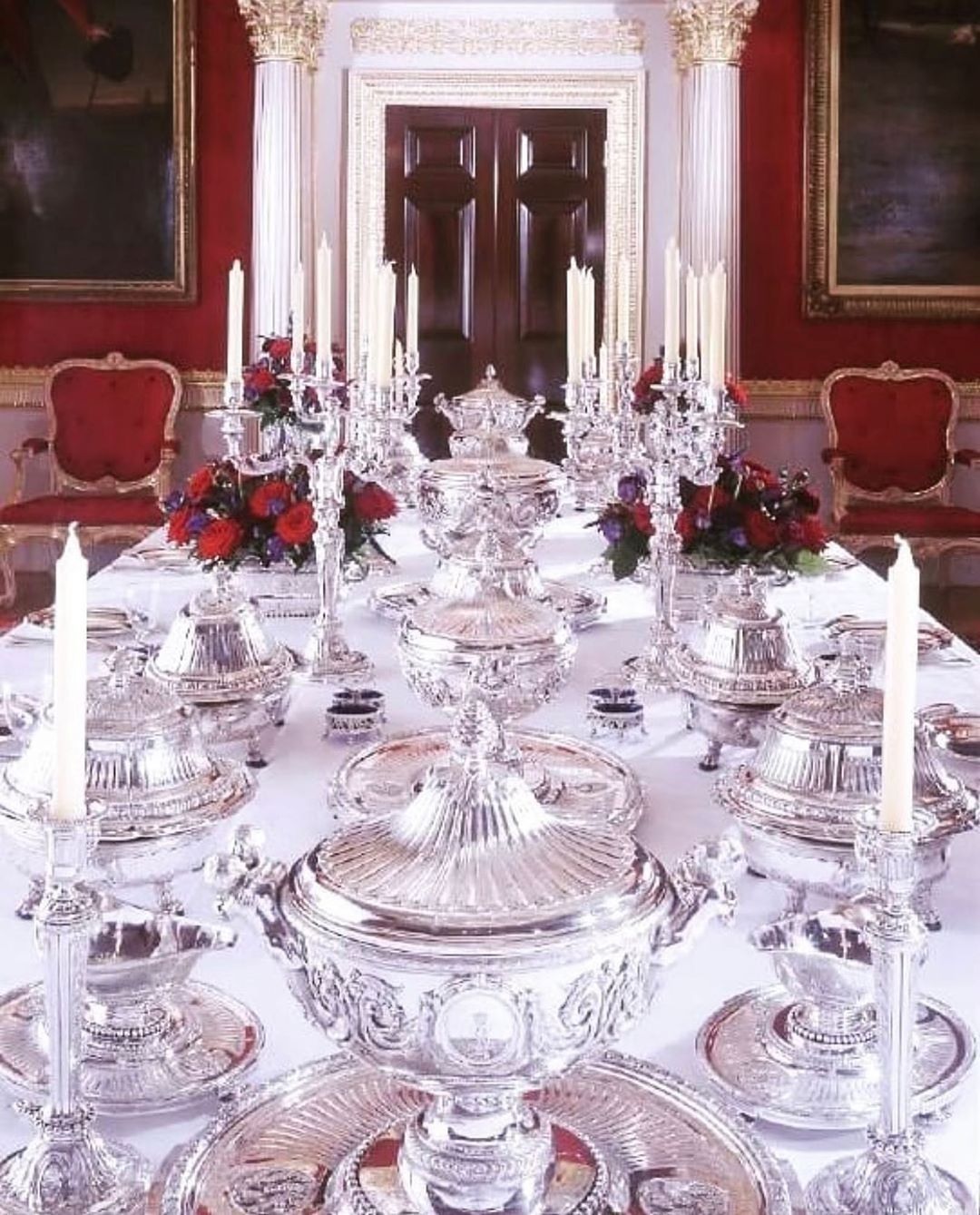 a dining room table is set with silver dishes and candles