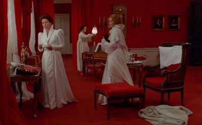 two women in white dresses standing in a red room