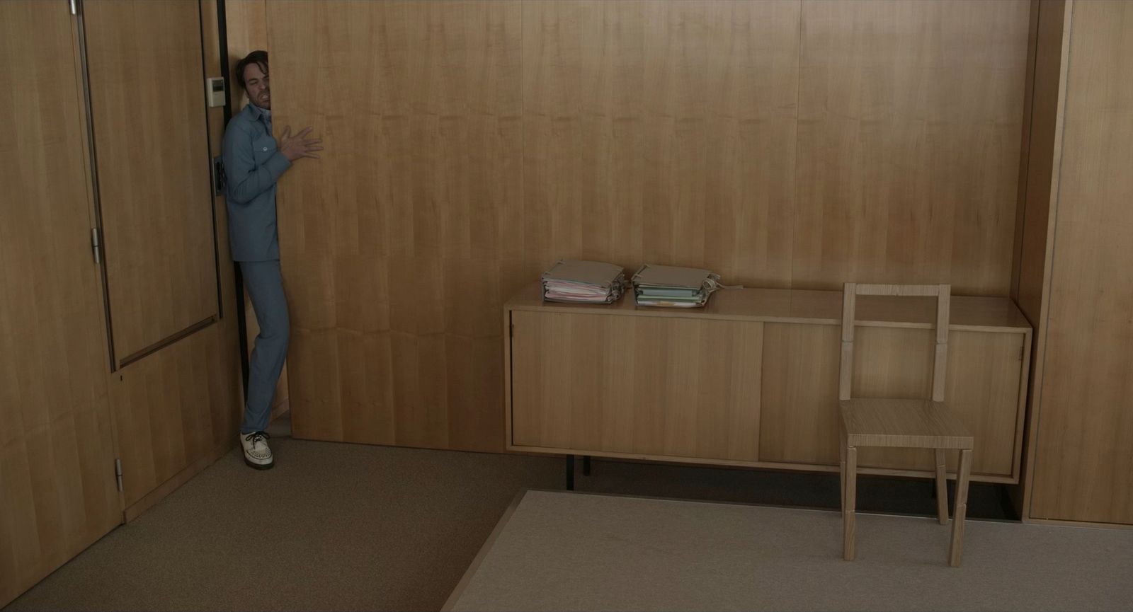 a woman standing in a room next to a wooden cabinet