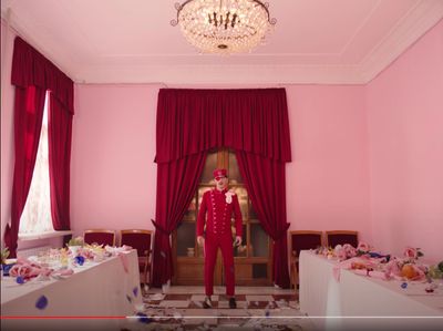 a person in a room with pink walls and a chandelier