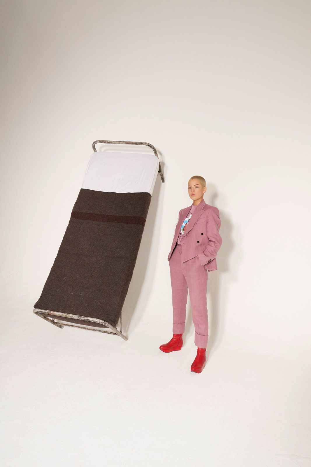 a woman in a pink suit standing next to a bed