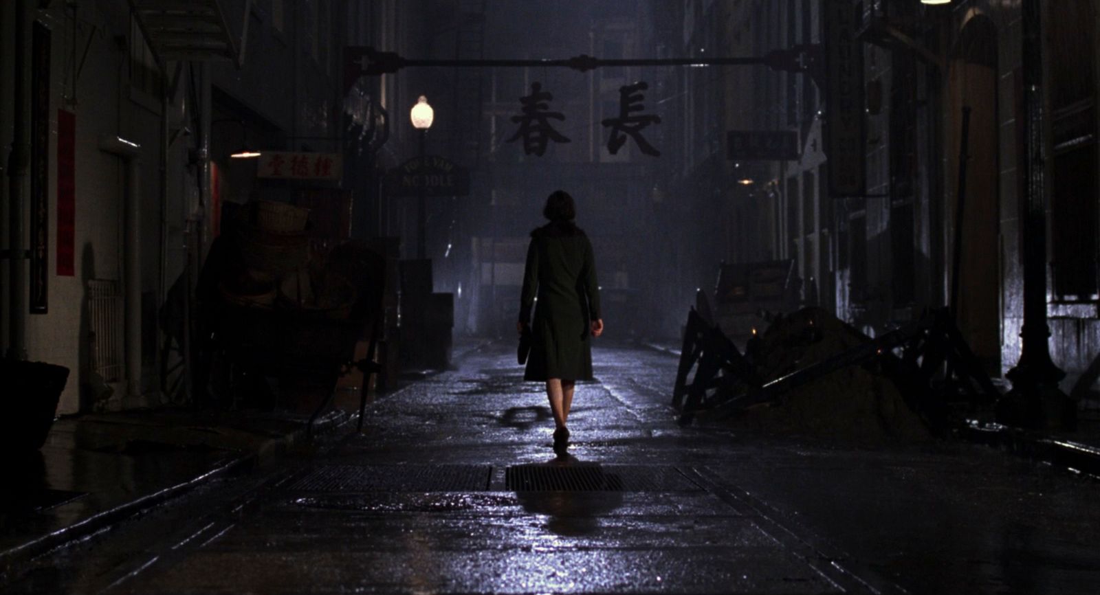 a woman walking down a dark street at night