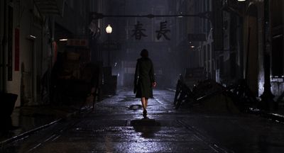 a woman walking down a dark street at night