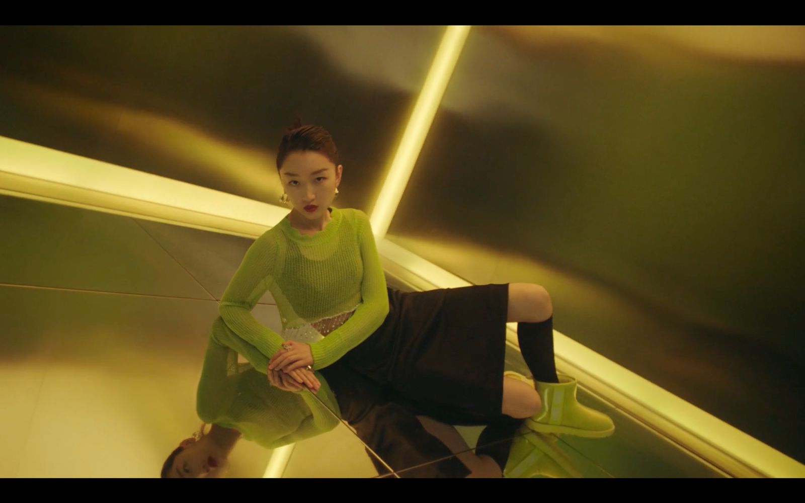 a woman in a green shirt and black skirt sitting on an escalator