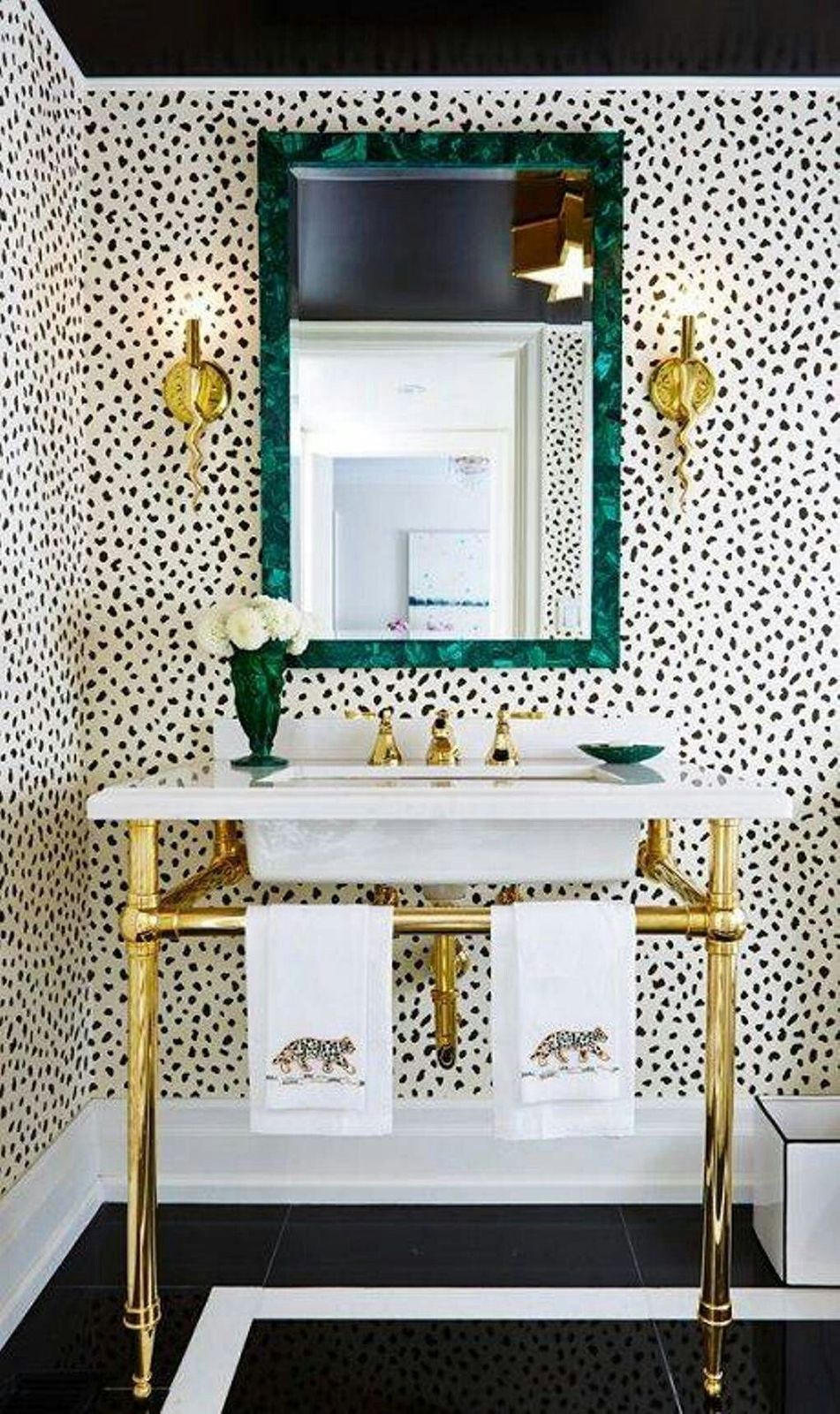 a bathroom with black and white wallpaper and gold fixtures