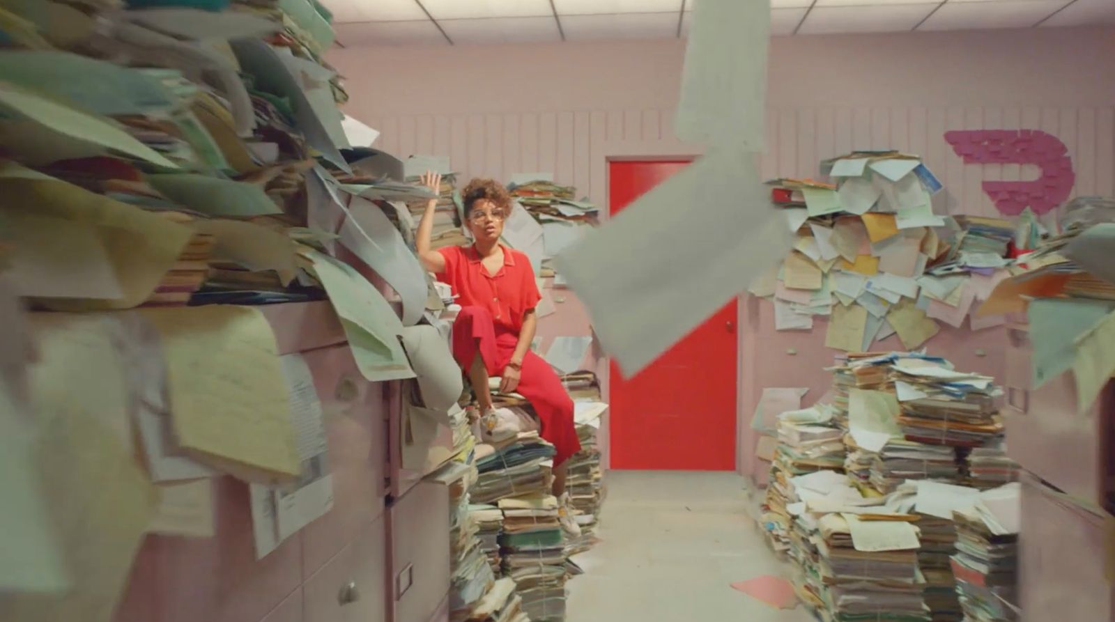 a woman sitting on a stack of files in an office