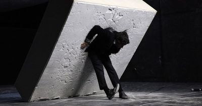 a man leaning against a wall in a dark room