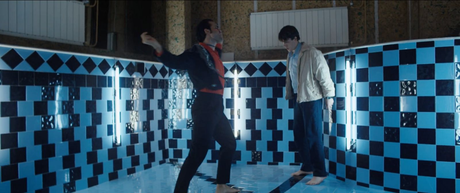 a couple of men standing next to each other in a bathroom