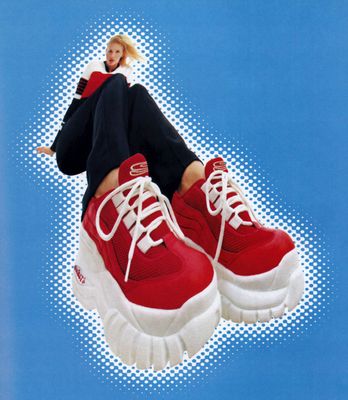 a woman laying on top of a pair of red sneakers