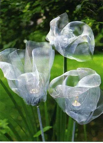 three clear plastic flowers in a garden