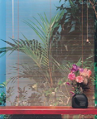 a red bench with a vase of flowers on top of it