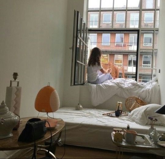 a woman sitting on a bed looking out a window