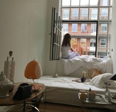 a woman sitting on a bed looking out a window