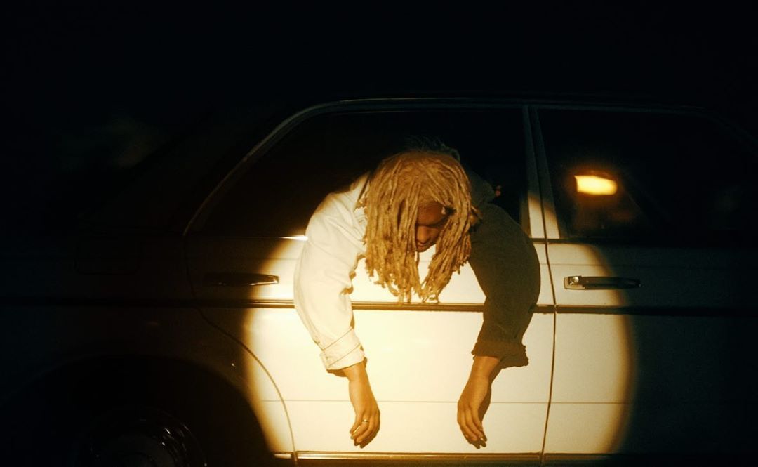 a man with dreadlocks leaning out of a car window