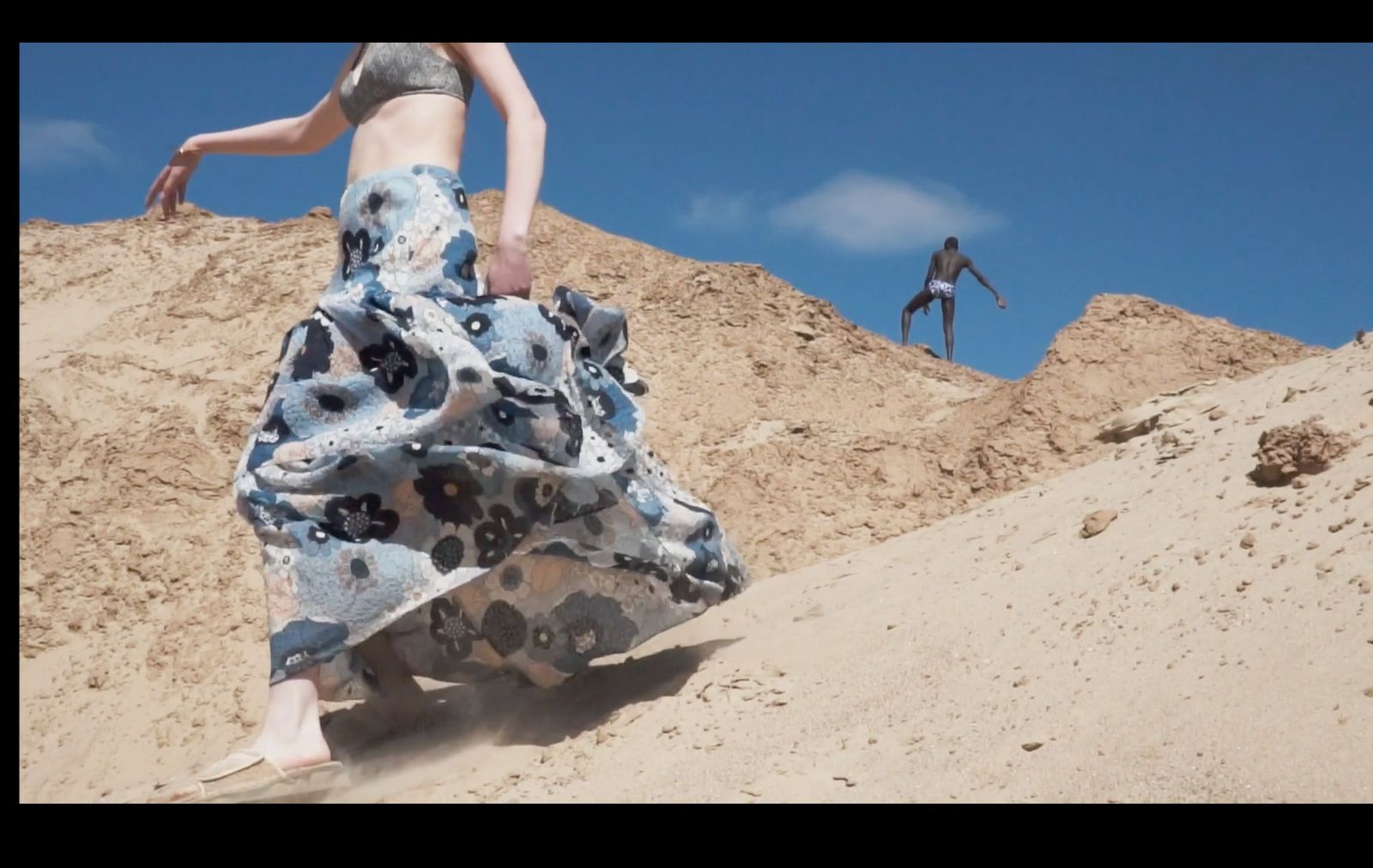 a woman in a long dress running up a hill