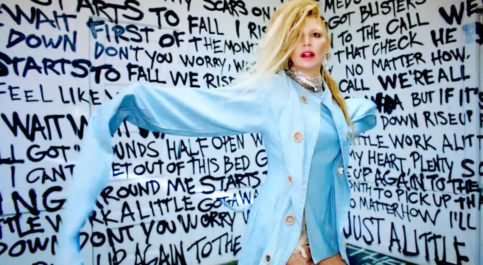 a woman standing in front of a wall covered in words