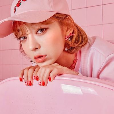 a woman in a pink hat leaning on a pink suitcase