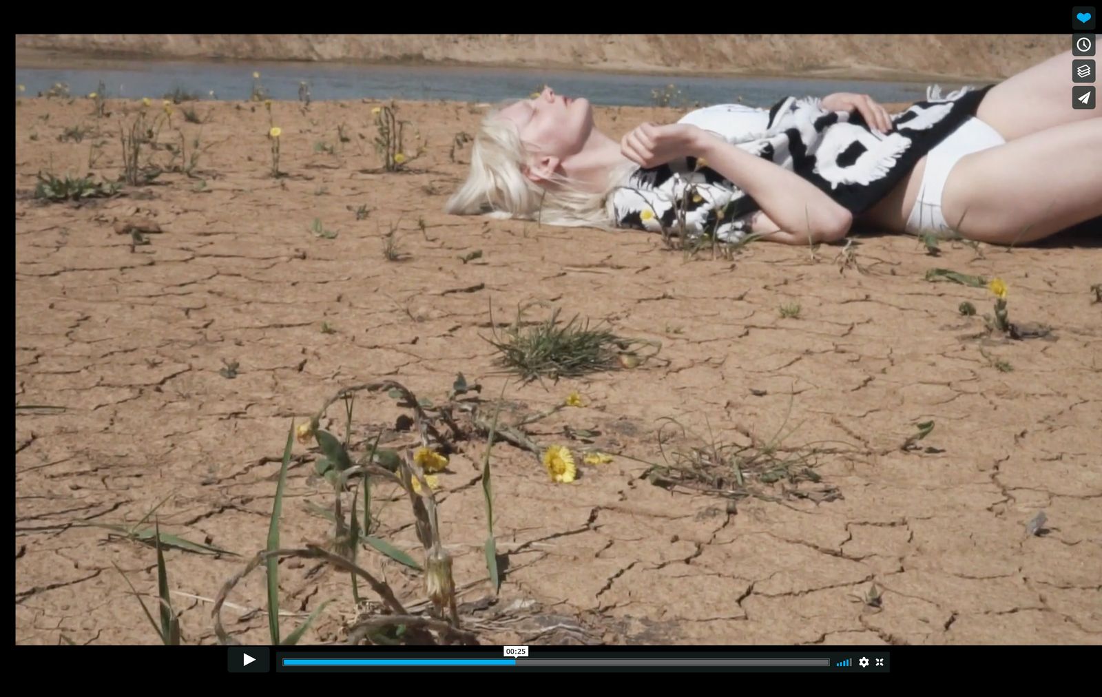 a woman laying on the ground next to a body of water