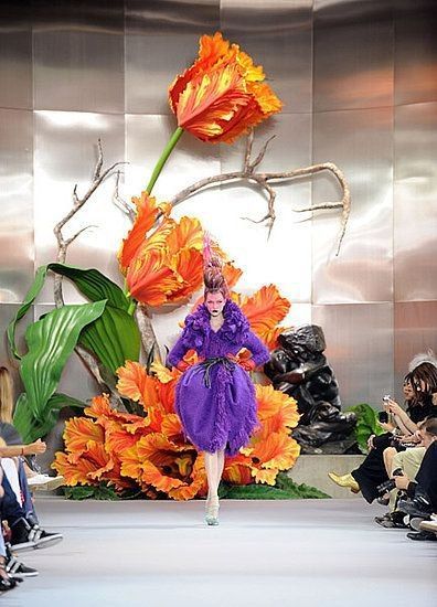 a woman in a purple dress walking down a runway