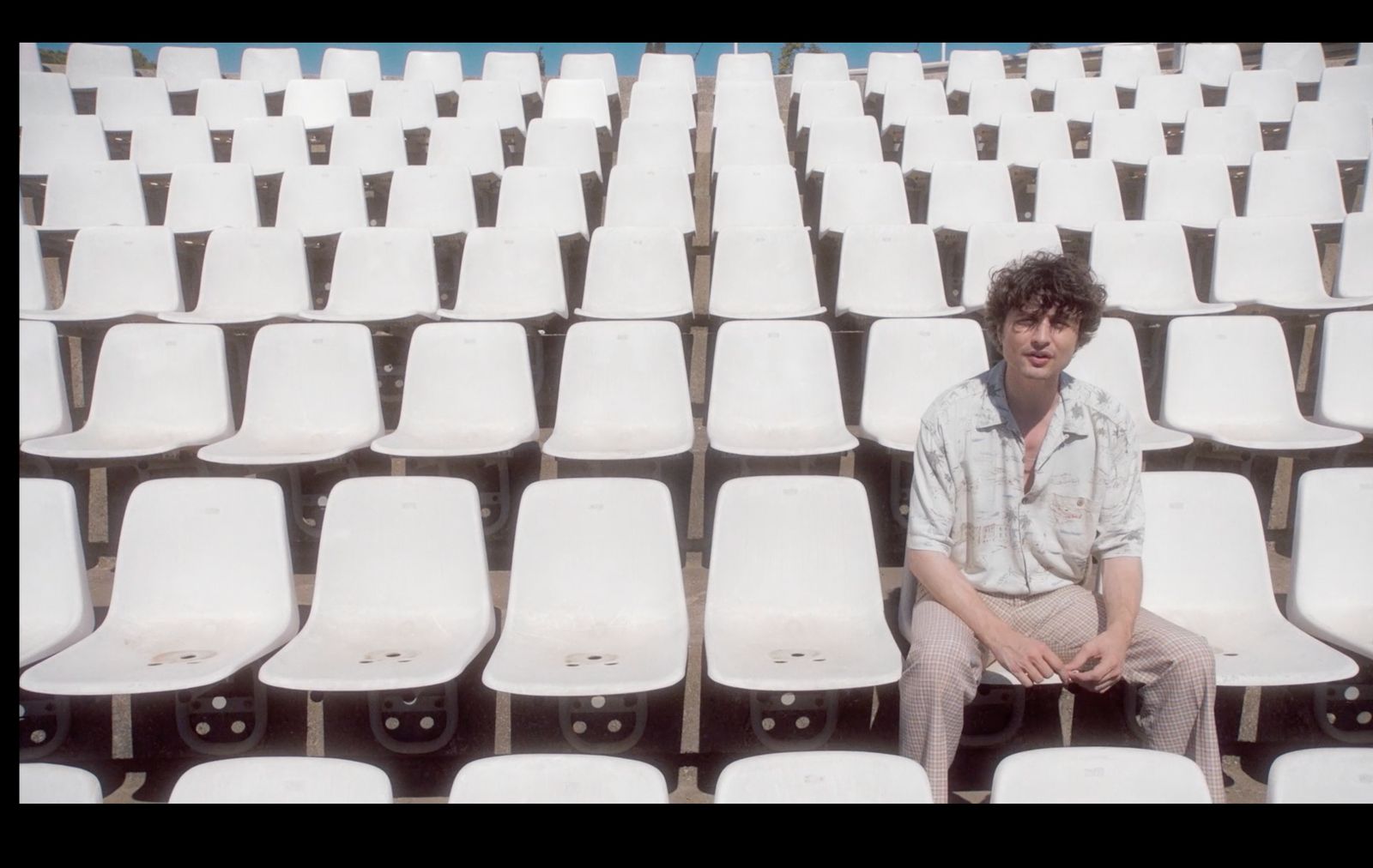 a man sitting in a row of white chairs