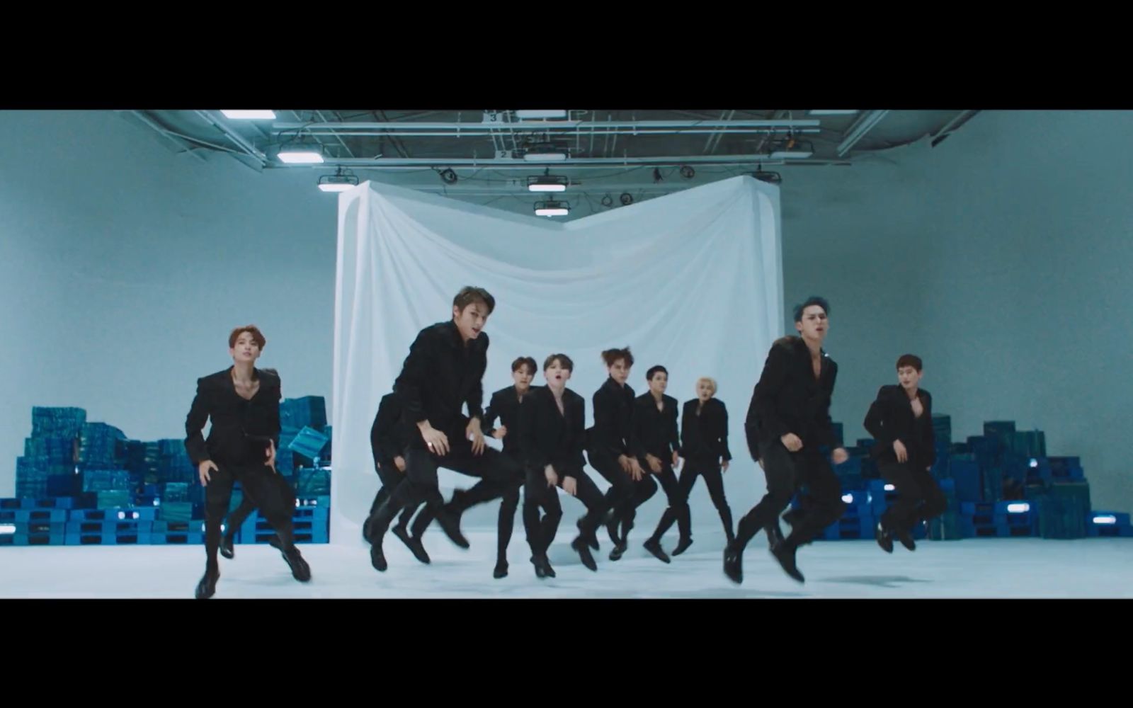 a group of men in black suits jumping in the air