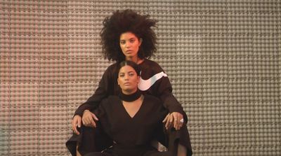 a woman sitting in a chair next to another woman