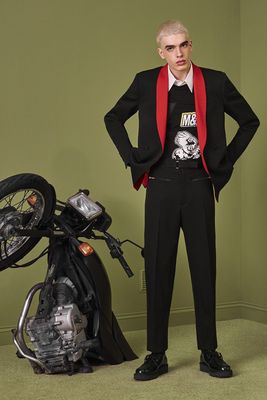 a man in a suit standing next to a motorcycle