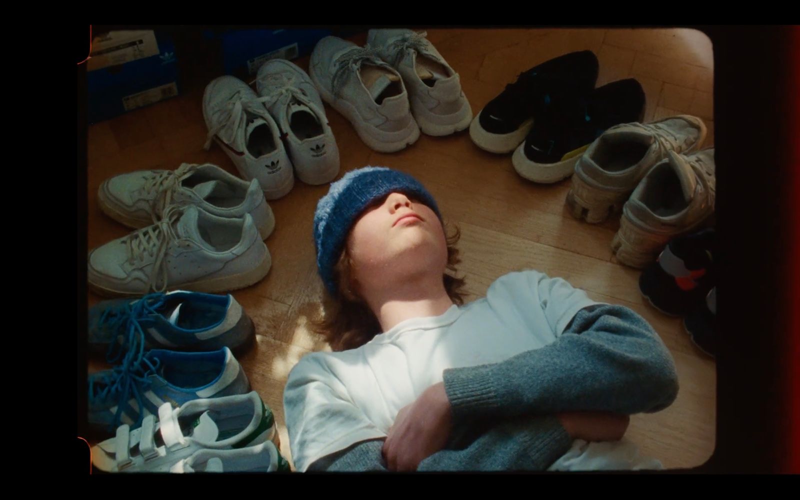 a young boy laying on the floor surrounded by shoes