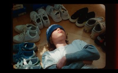 a young boy laying on the floor surrounded by shoes