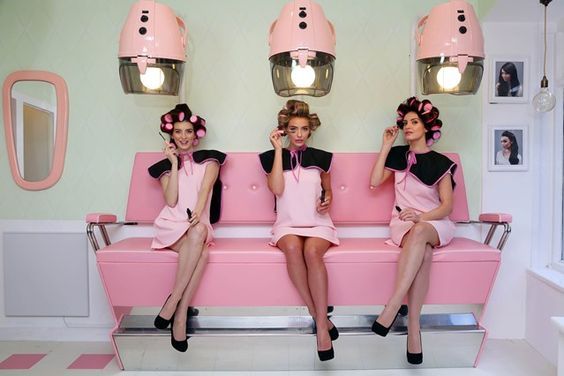 a group of women sitting on top of a pink couch