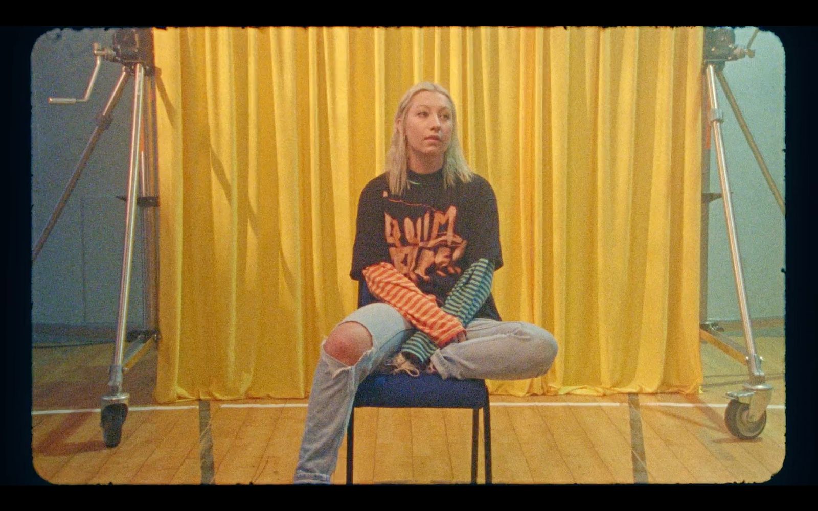 a woman sitting on a chair in front of a yellow curtain