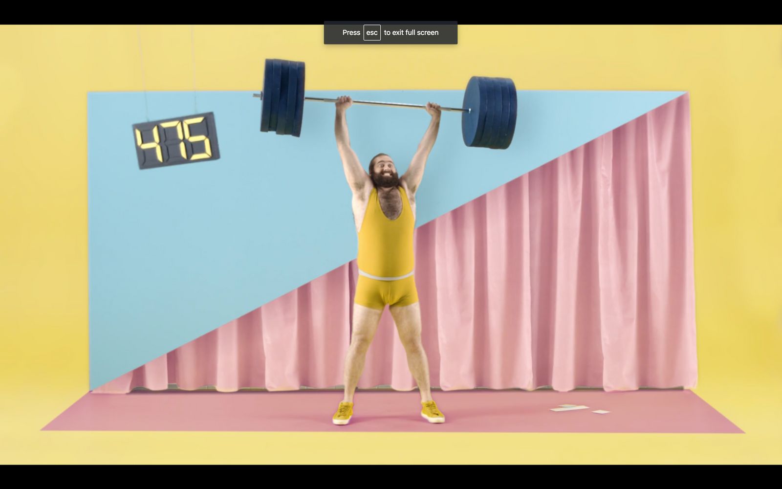 a man in a yellow bodysuit lifting a barbell