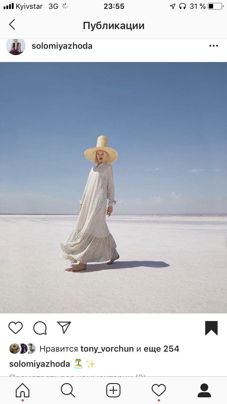 a woman in a white dress and hat walking across a field