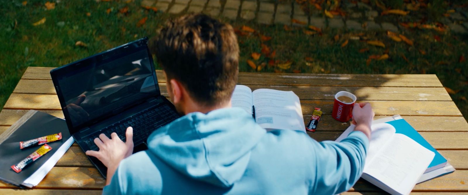 a man sitting at a picnic table using a laptop computer