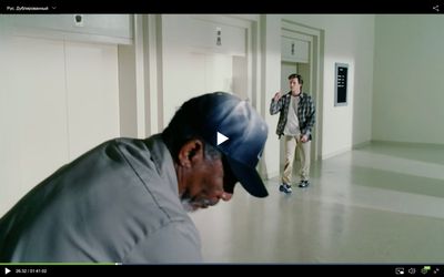 a man in a baseball cap looking at another man in a hallway