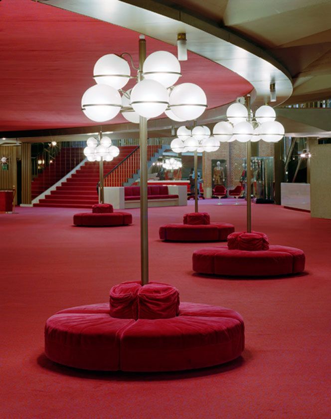 a red carpeted room with round seating and lights