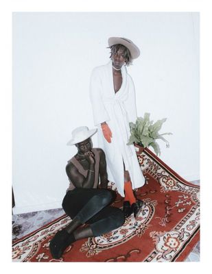 a woman in a white coat and hat sitting on a rug next to a man