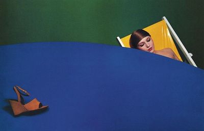 a woman laying on a blue table next to a pair of shoes