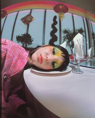 a woman with makeup on her face sitting at a table