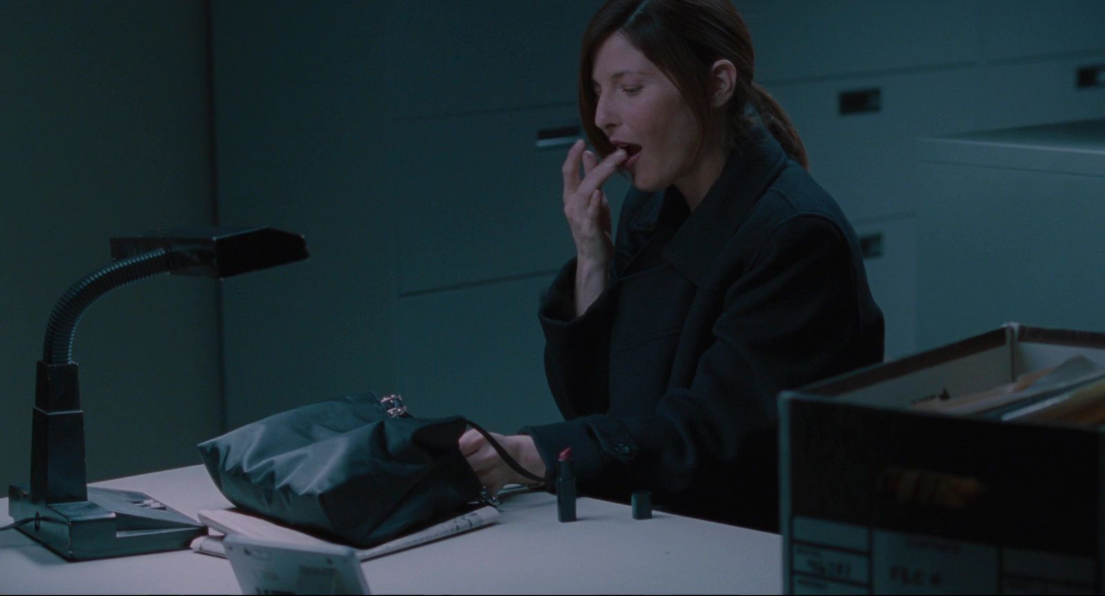 a woman sitting at a desk smoking a cigarette