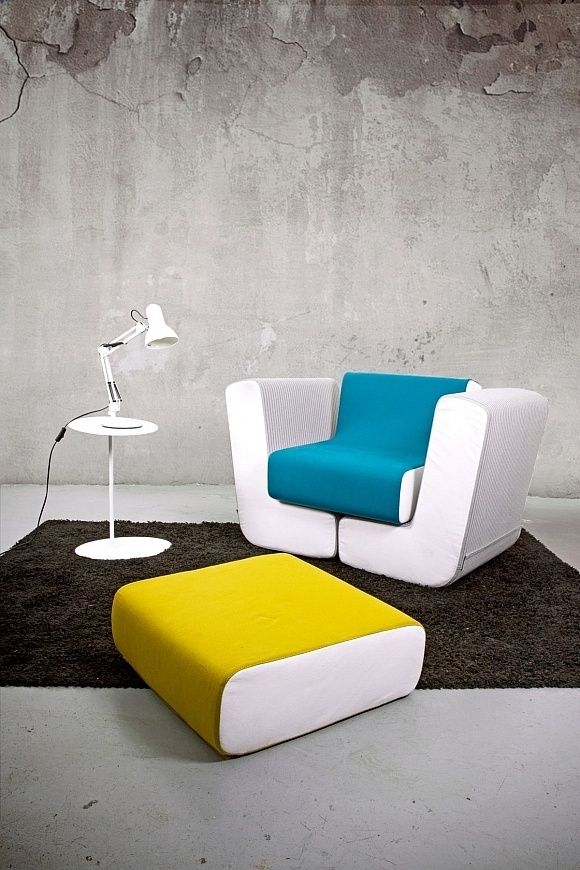 a chair and ottoman in a room with a concrete wall