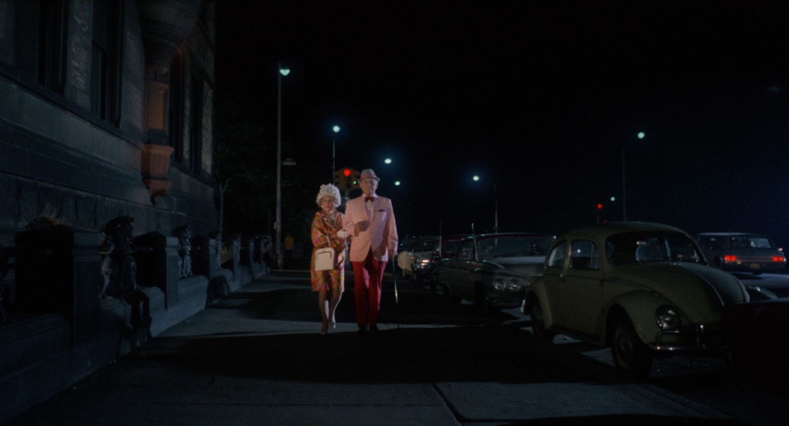 a man and woman walking down a street at night