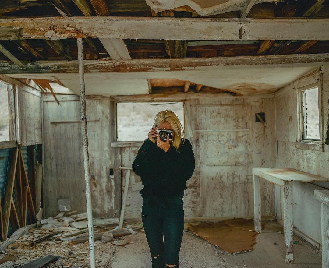 a woman taking a picture of herself in a run down house