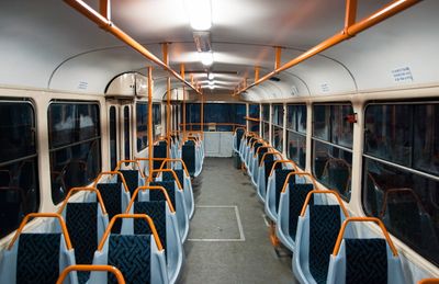 an empty train car with blue seats and orange railings