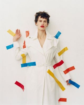 a woman in a white trench coat with colored strips on her body