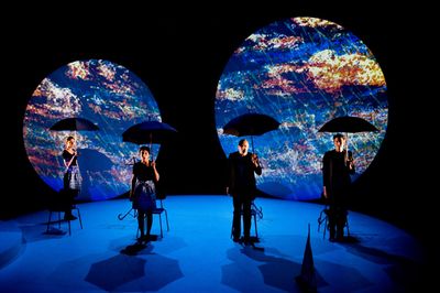 a group of people standing on a stage holding umbrellas