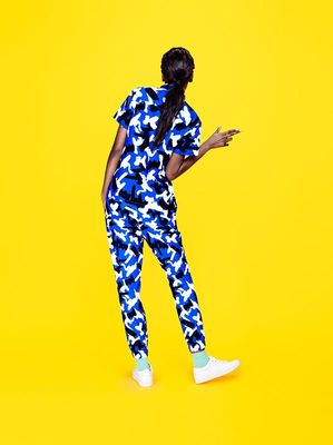 a woman in a blue and white jumpsuit looking at her cell phone