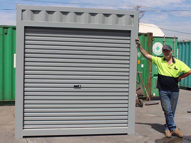 a man in a yellow shirt is standing next to a metal door